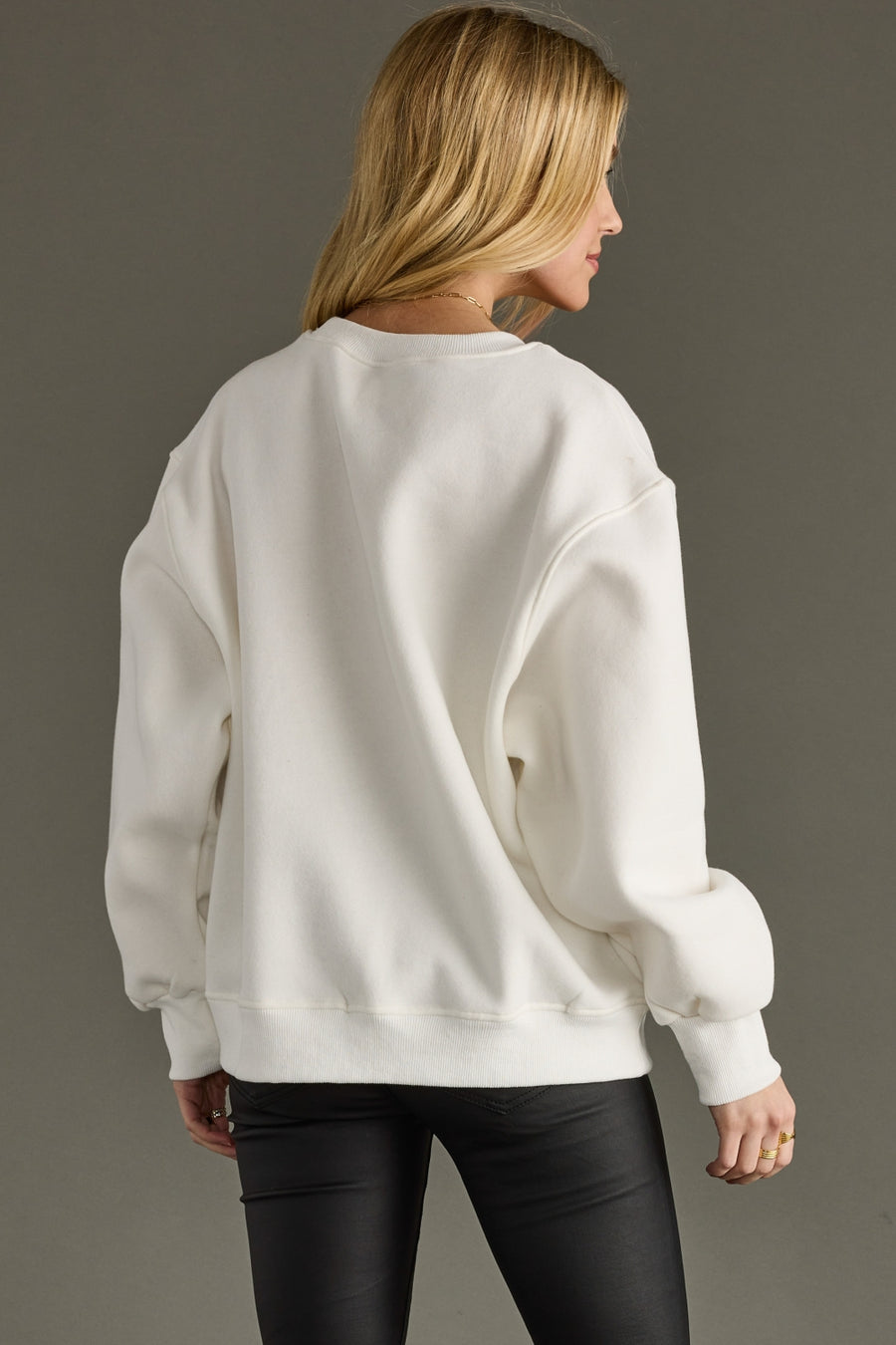 Person wearing a white sweatshirt against a gray background