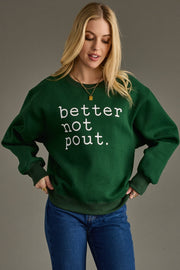 Woman wearing a green sweatshirt with 'better not pout' text on a gray background