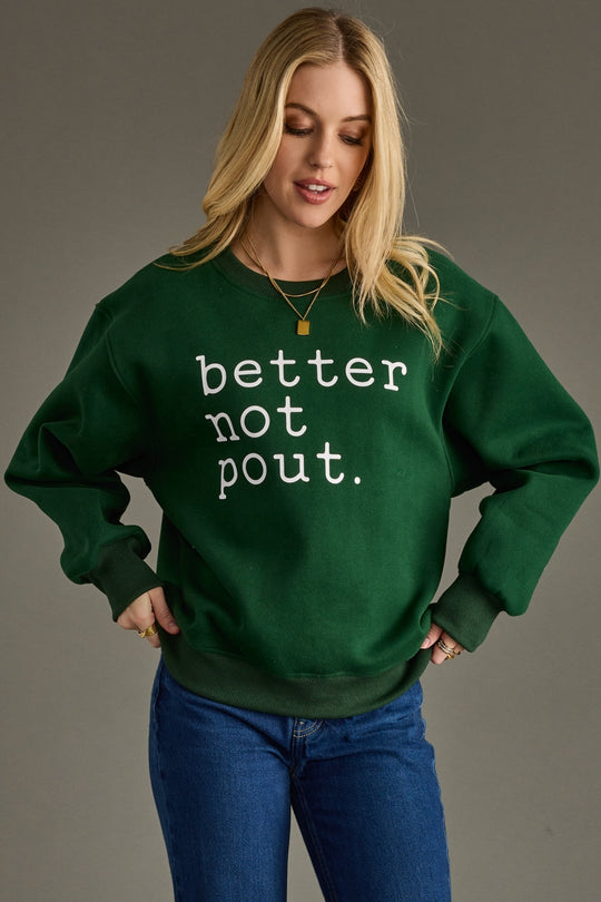 Woman wearing a green sweatshirt with 'better not pout' text on a gray background