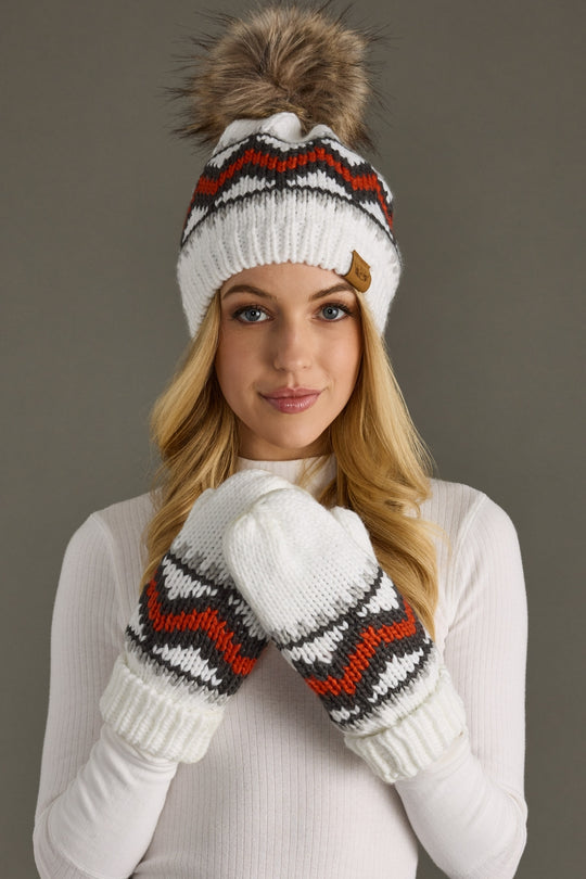 Woman wearing a white knit hat with a pom-pom and matching mittens against a gray background