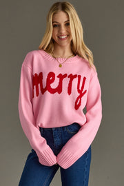 Woman wearing a pink sweater with red 'Merry' text against a gray background