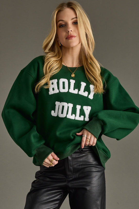 Woman wearing a green 'Holly Jolly' sweater against a gray background