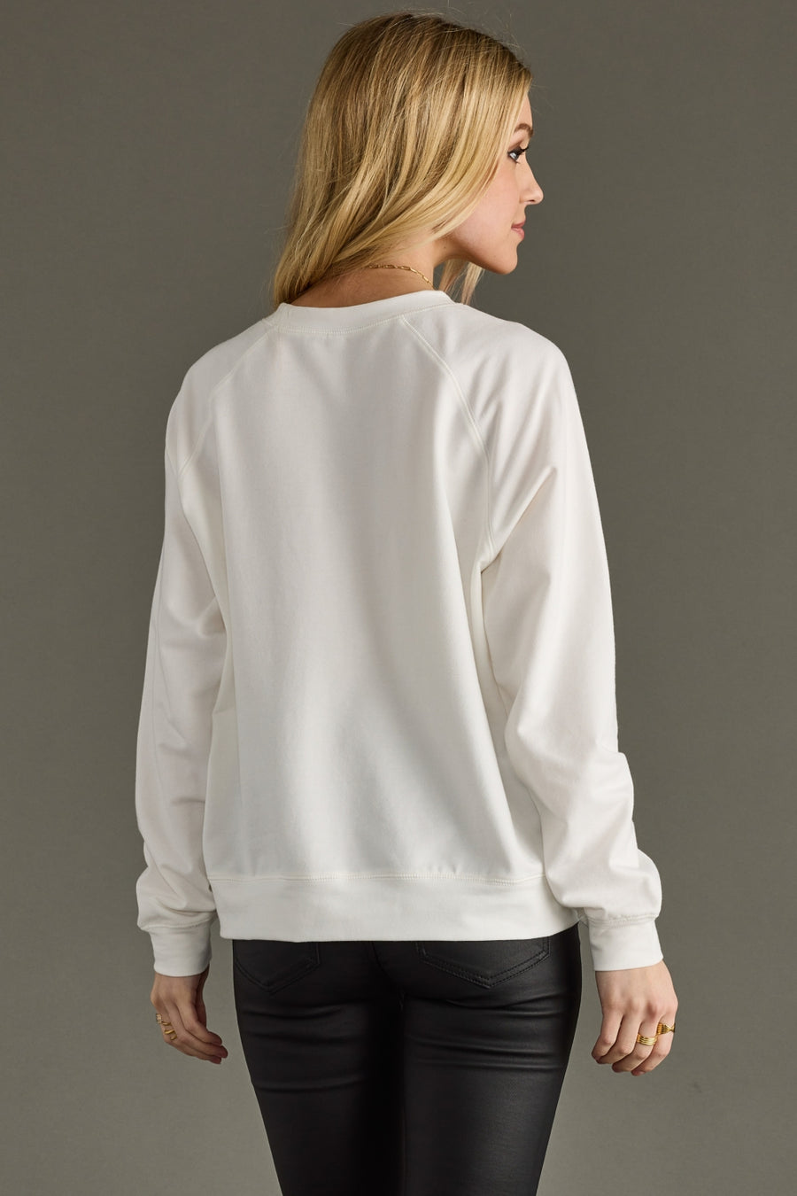 Woman wearing a white sweatshirt against a gray background