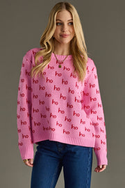 Woman wearing a pink sweater with 'ho ho ho' pattern against a gray background