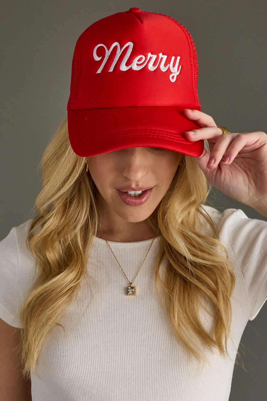 Person wearing a red cap with 'Merry' text, holding it above their head.