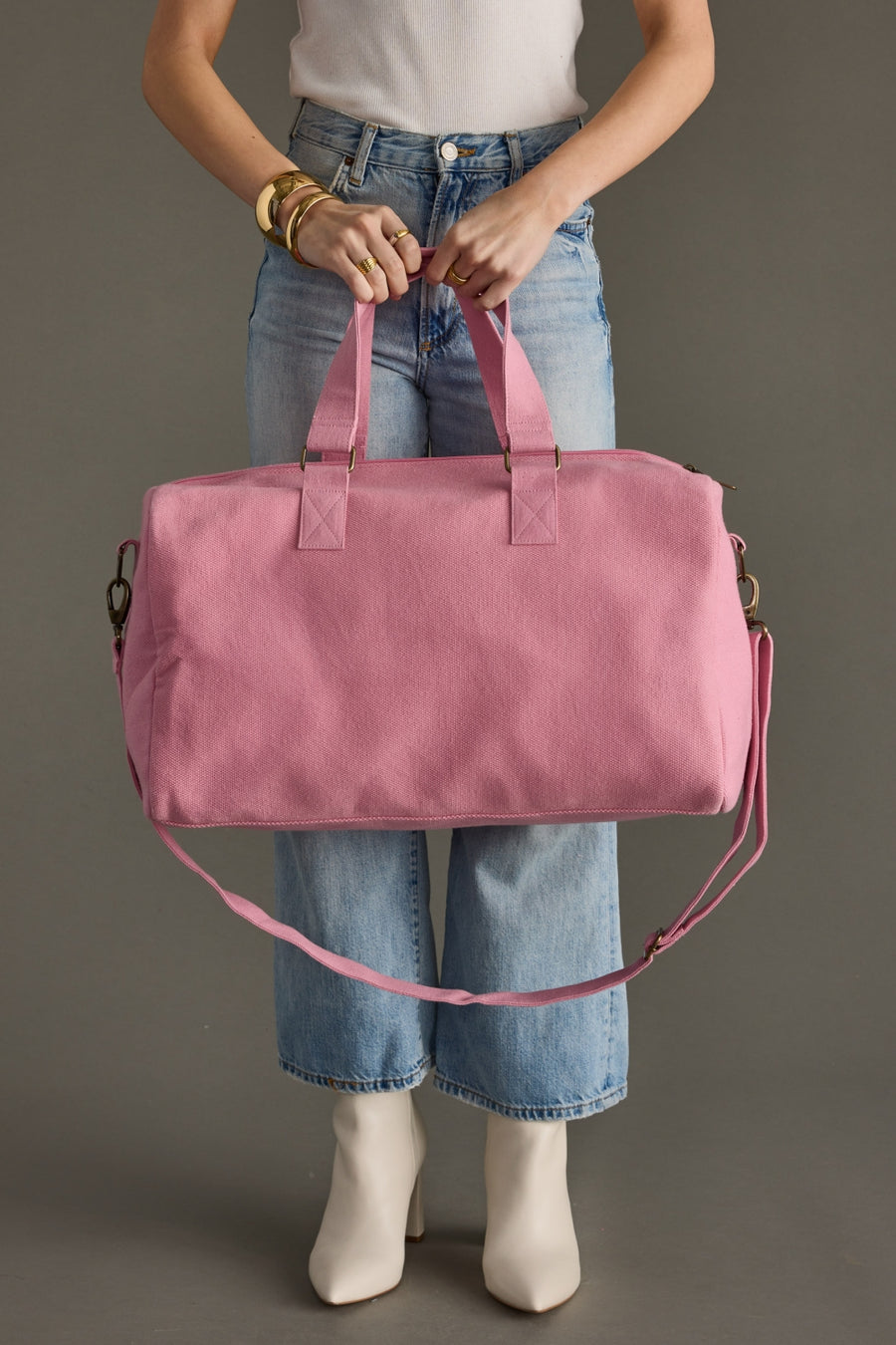 Person holding a pink duffel bag against a neutral background