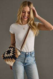 Woman holding a patterned handbag against a gray background