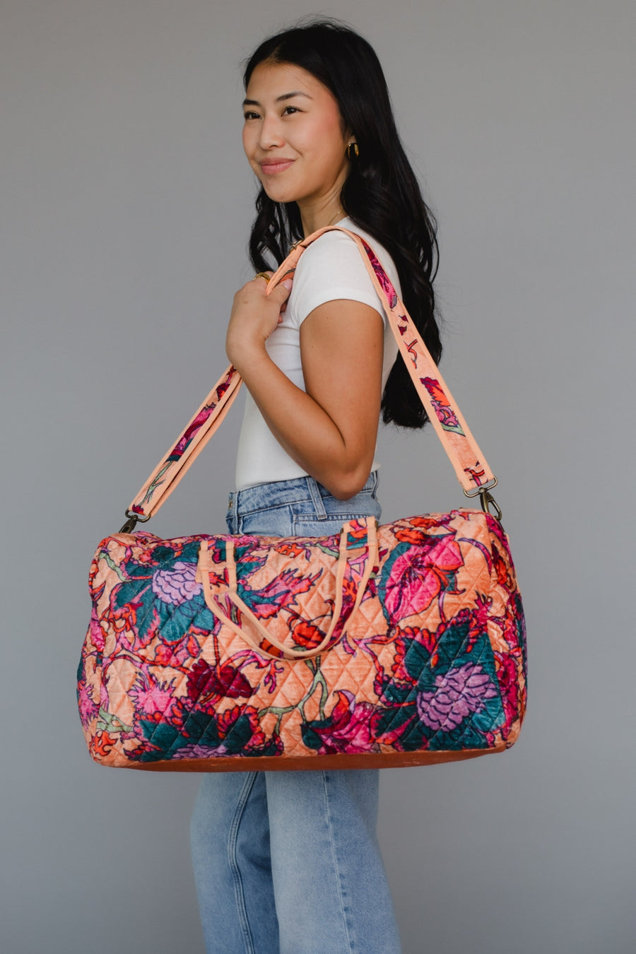 Woman holding a colorful floral-patterned bag against a gray background