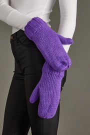 Purple knitted gloves worn by a person against a neutral background
