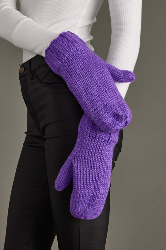 Purple knitted gloves worn by a person against a neutral background