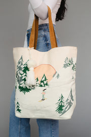 Tote bag with nature-themed design held by a person wearing jeans