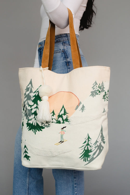 Tote bag with nature-themed design held by a person wearing jeans