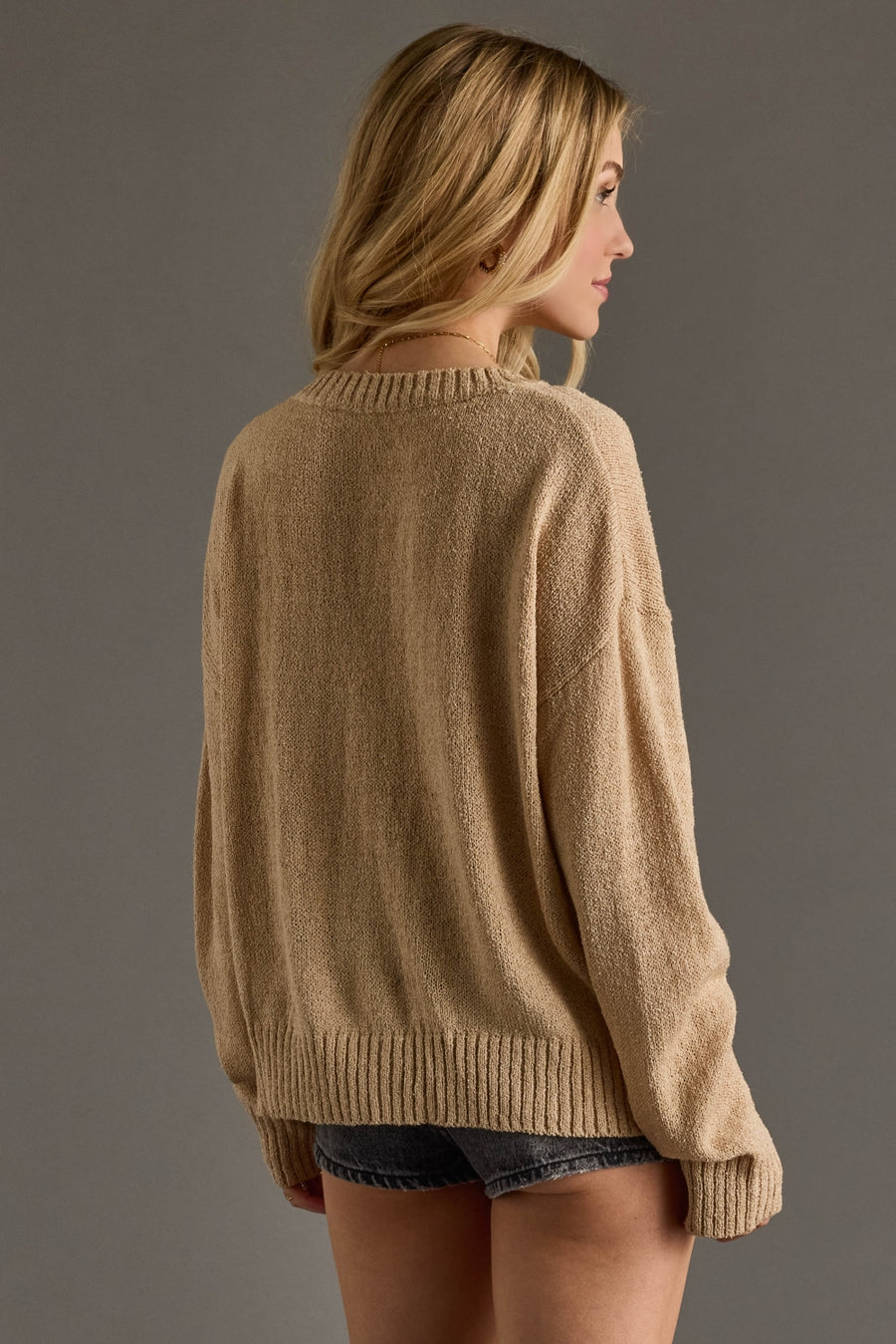 A cozy tan knit sweater featuring bold black “Whiskey Weather” lettering across the front for a fun, fall-ready statement. Designed with a relaxed, easy fit and a soft textured knit, it includes a classic crew neckline, long sleeves, and ribbed cuffs and hem for comfortable everyday wear. Perfect for layering or wearing on its own, this sweater pairs effortlessly with denim for a warm, casual seasonal look.