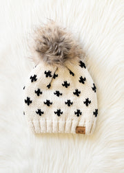 Knit beanie with black pattern and gray pom-pom on a white surface