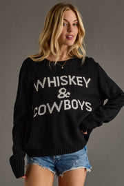 Woman wearing a black sweater with 'Whiskey & Cowboys' text on a gray background