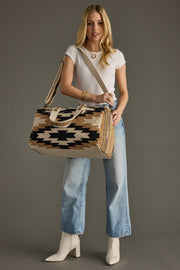 Woman holding a patterned handbag against a gray background