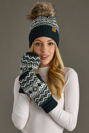 Woman wearing a dark teal and white patterned beanie and mittens against a gray background