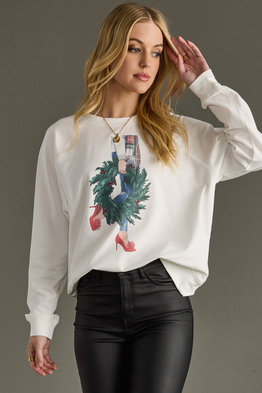 Woman wearing a white sweatshirt with a graphic design on a gray background