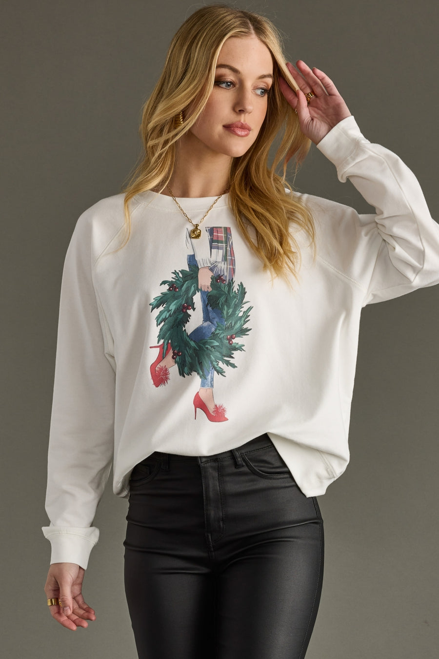 Woman wearing a white sweatshirt with a graphic design on a gray background