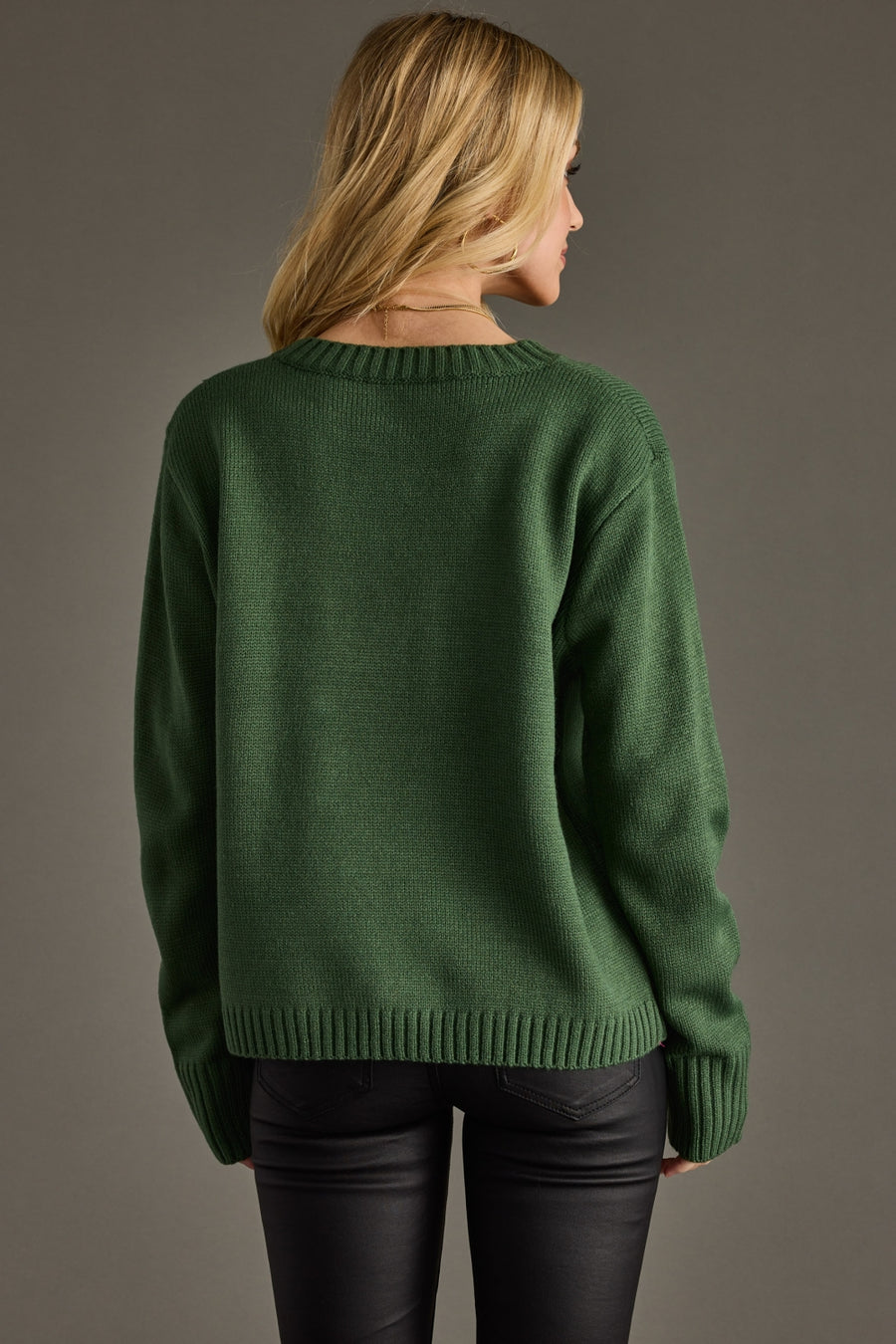 Person wearing a green sweater against a gray background