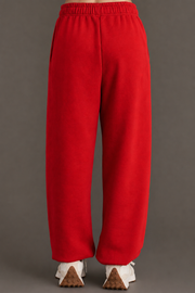 A person wearing Red Panache Sweatpants from the Panache Apparel Collection and white sneakers stands on a gray surface, facing away from the camera. The sweatpants have a relaxed fit with an elastic waistband and offer a loose, comfortable silhouette.
