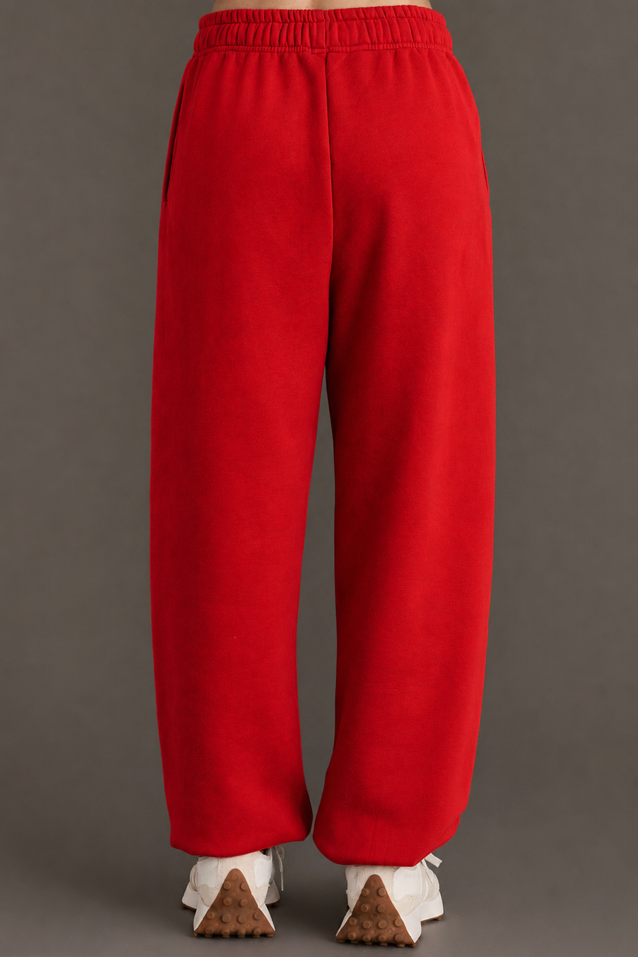 A person wearing Red Panache Sweatpants from the Panache Apparel Collection and white sneakers stands on a gray surface, facing away from the camera. The sweatpants have a relaxed fit with an elastic waistband and offer a loose, comfortable silhouette.