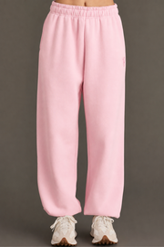 Individual dressed in Panache Apparel Collection’s Light Pink Panache Sweatpants and white athletic shoes, standing against a plain dark background; only the lower half of the body is visible in the image.