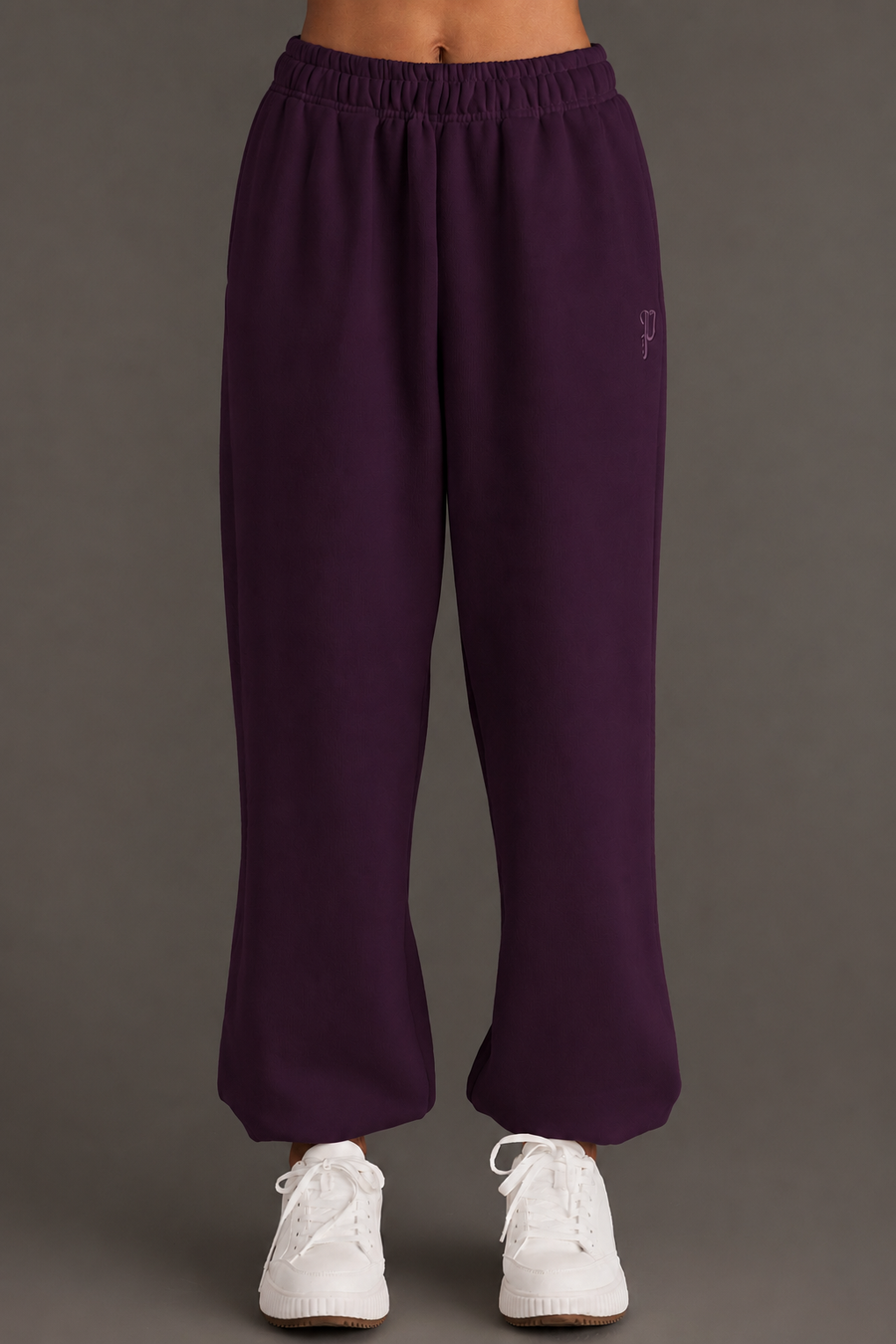 A model showcases the Panache Apparel Collection Plum Panache Sweatpants, featuring a relaxed fit and elastic waistband, paired with white sneakers. The photo displays only the lower torso and legs against a simple, neutral background.