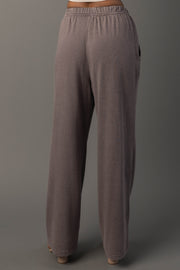 A person wearing Panache Apparel Collection’s Gray Washed Soft Sweatpants. Featuring a loose fit, high waist, wide legs, and an elastic waistband, and stands against a plain gray background.