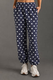 A person wearing Panache Apparel Collection’s Navy & White Polka Dot Sweatpants and white sneakers stands against a gray background.