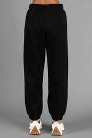 Model wearing Black Panache Sweatpants from the Panache Apparel Collection with white sneakers, shown from the back against a plain gray background.