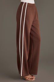 Brown Lounge Sweatpants featuring a wide-leg fit, two white vertical side stripes, and an elastic waistband.