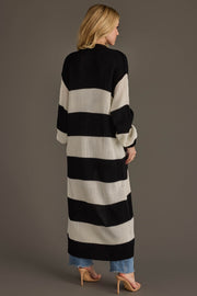 A woman with blonde hair stands with her back to the camera against a plain background, wearing jeans, heels, and the Panache Apparel Collection Black & White Striped Duster Cardigan.