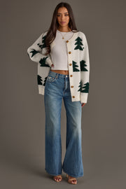 White Button Up Tree Cardigan in white with green tree patterns, worn over a white crop top and wide-leg blue jeans.