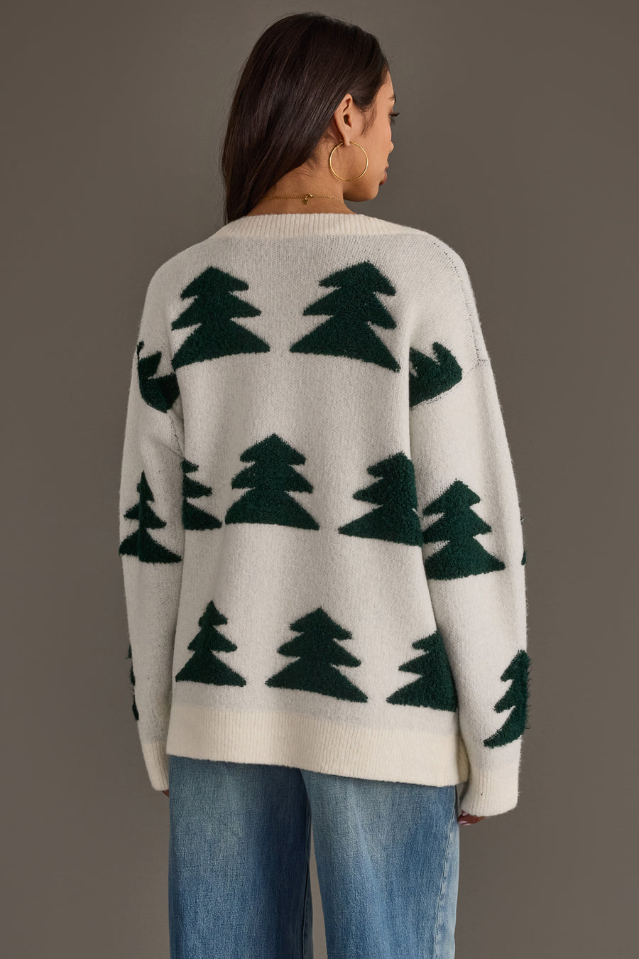 A person wearing a White Button Up Tree Cardigan from the Panache Apparel Collection, a white button-up cardigan patterned with green pine trees.