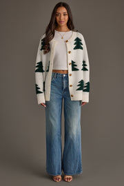 A woman wears a White Button Up Tree Cardigan over a white tank top, paired with wide-leg blue jeans.