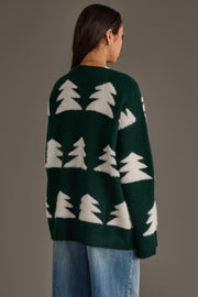 A person wears a Green Button Up Tree Cardigan from the Panache Apparel Collection, featuring a dark green, button-up design with a repeating white pattern of stylized evergreen trees.