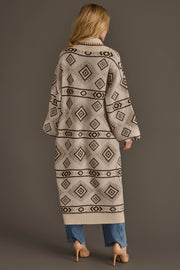 A woman with long blonde hair models the Cream & Brown Western Cardigan from Panache Apparel Collection, pairing it with blue jeans and nude heels. She stands against a plain brown background, facing away from the camera.