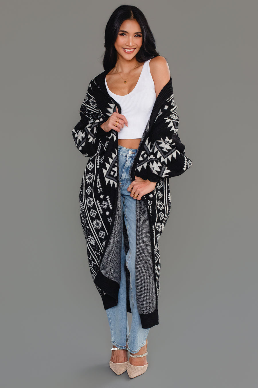 Woman styling Panache Apparel’s black and white Western cardigan off the shoulder over a white crop top and jeans.