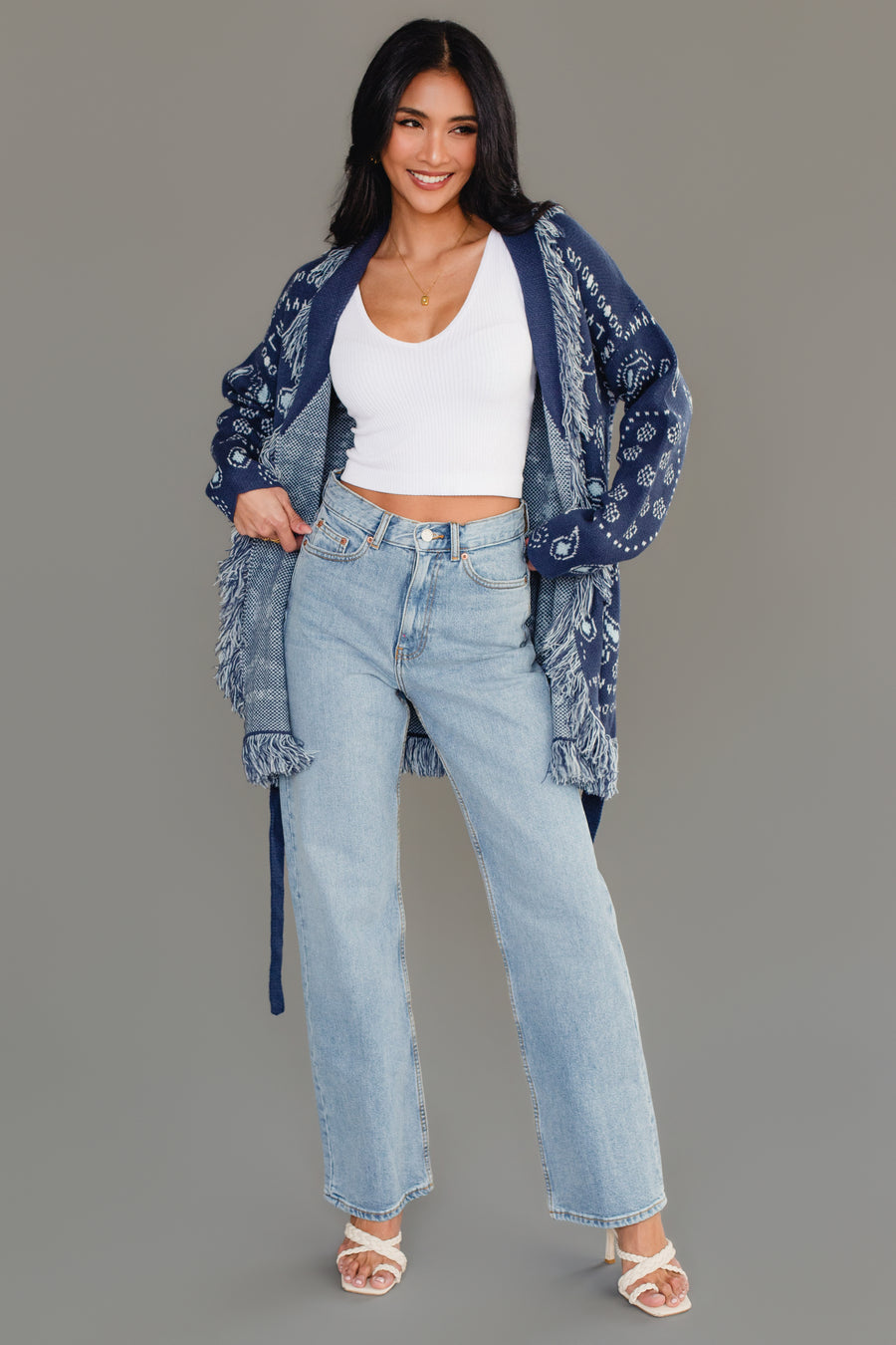 Full-body studio image of Panache Apparel’s blue bandana fringe cardigan worn open with light wash jeans.