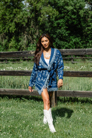 Full-body outdoor view of Panache Apparel’s blue bandana fringe cardigan with fringe trim and tie waist.