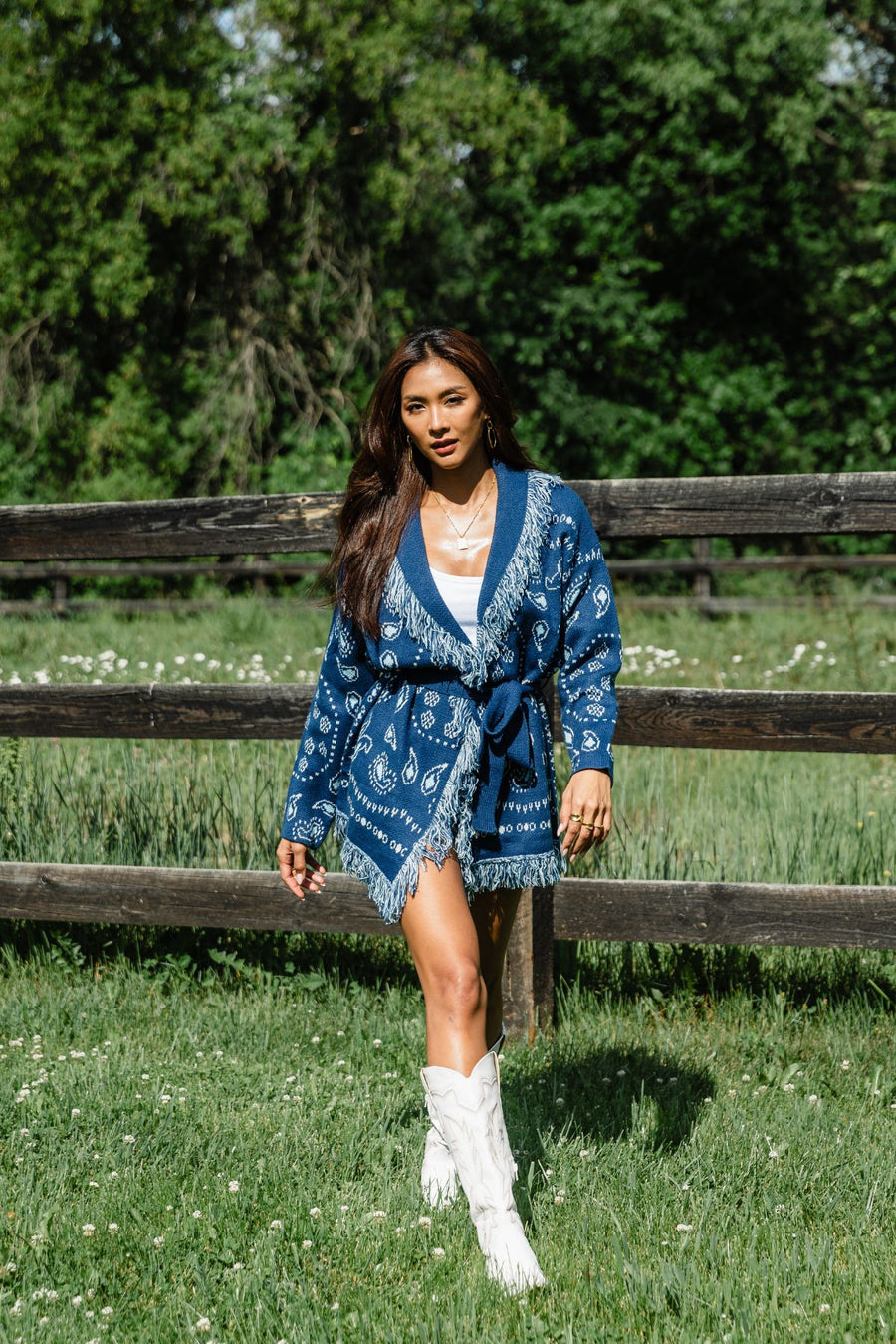 Full-body outdoor view of Panache Apparel’s blue bandana fringe cardigan with fringe trim and tie waist.