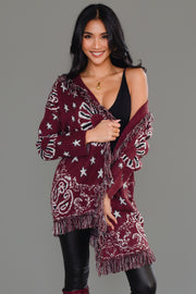 Woman wearing Panache Apparel’s burgundy bandana fringe cardigan draped off one shoulder, front view.