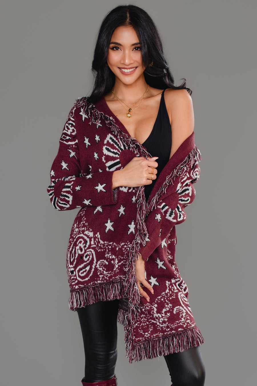 Woman wearing Panache Apparel’s burgundy bandana fringe cardigan draped off one shoulder, front view.