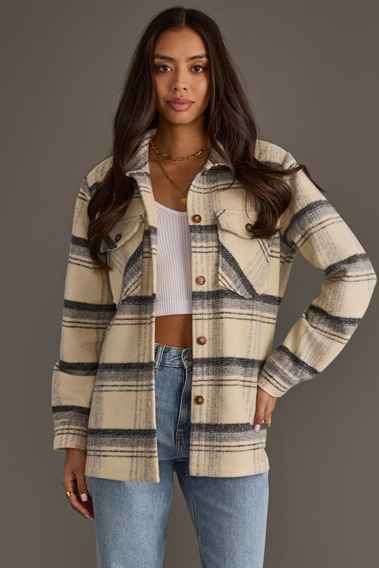 A woman models the Panache Apparel Collection Cream, Black & Gray Plaid Jacket over a white crop top and blue jeans, standing against a plain gray background with her hand on her hip.