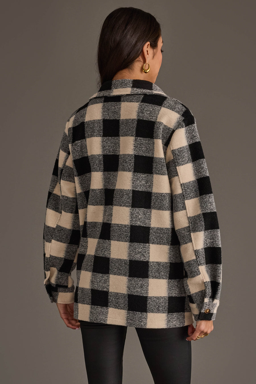 A woman is seen from behind wearing the Panache Apparel Collection Black & Cream Plaid Jacket with long sleeves, paired with black pants. She has long brown hair styled down and accessorizes with gold hoop earrings, set against a neutral background.