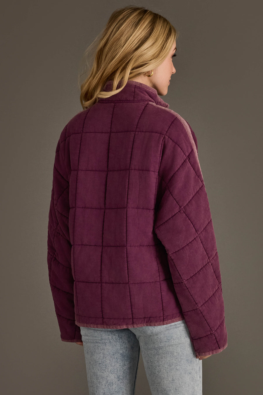 A person with blonde hair, seen from behind, wears the Plum Soft Quilted Jacket from Panache Apparel Collection paired with light blue jeans against a plain, neutral background.