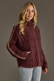 A woman wearing the Panache Apparel Collection Dark Brown Soft Quilted Jacket with tan stripes on the sleeves and light blue jeans, standing against a plain gray background.