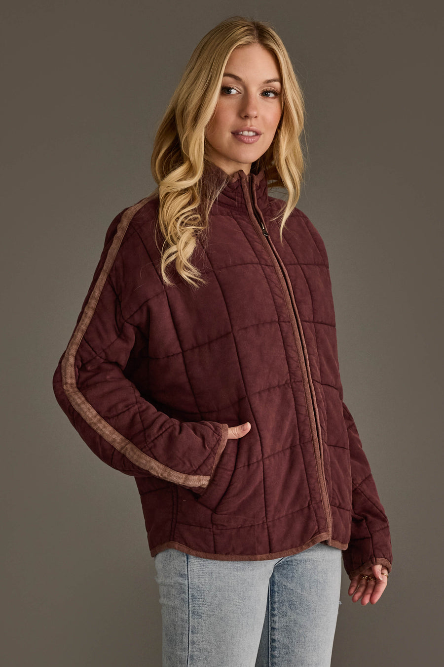 A woman wearing the Panache Apparel Collection Dark Brown Soft Quilted Jacket with tan stripes on the sleeves and light blue jeans, standing against a plain gray background.