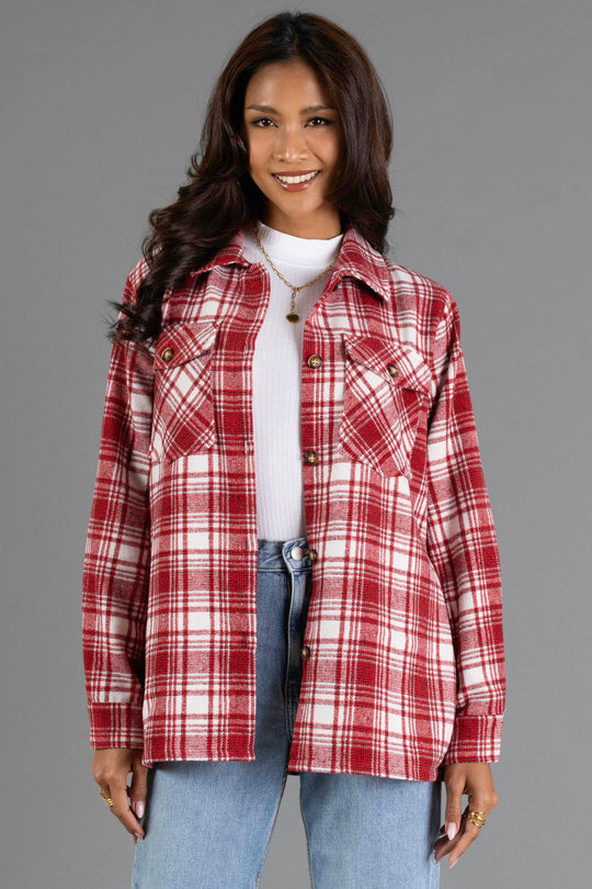 A woman with long dark hair wears the Panache Apparel Collection Red & White Plaid Jacket over a white top and blue jeans, standing and smiling in front of a gray background.